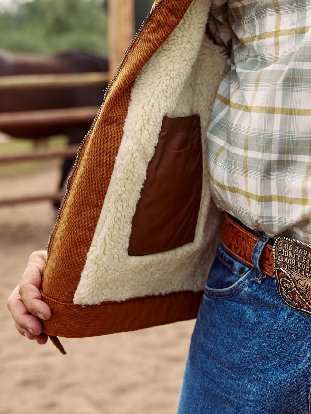 Tan canvas vest detail: cream sherpa-lined inner panel and metal zipper