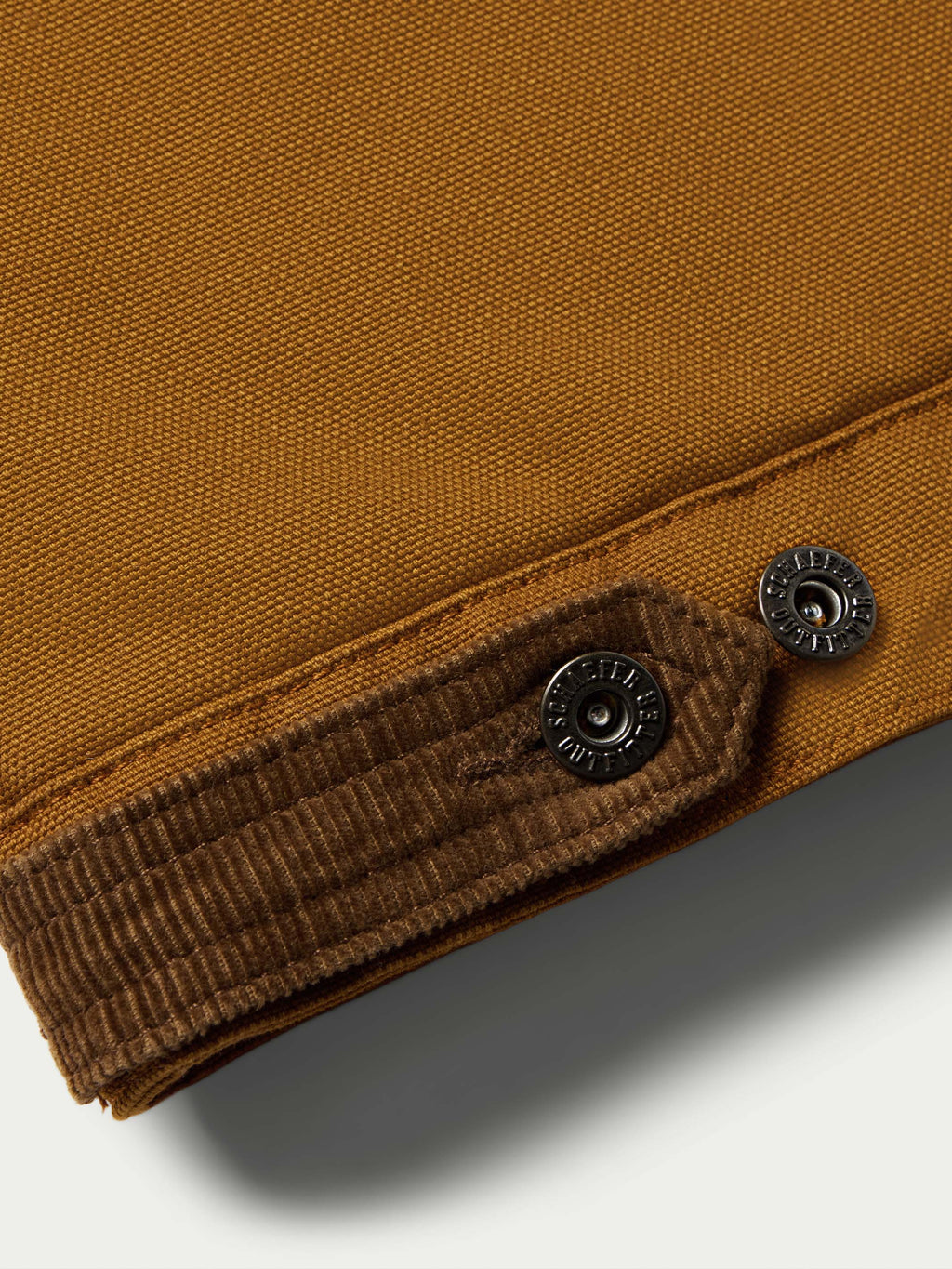 Sandstone canvas vest hem with dark ribbed lining and two snap buttons