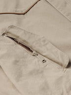 Beige coat fabric with brown-trimmed zipper pocket detail
