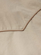 Beige coat fabric close-up with brown contrast piping and edge stitching