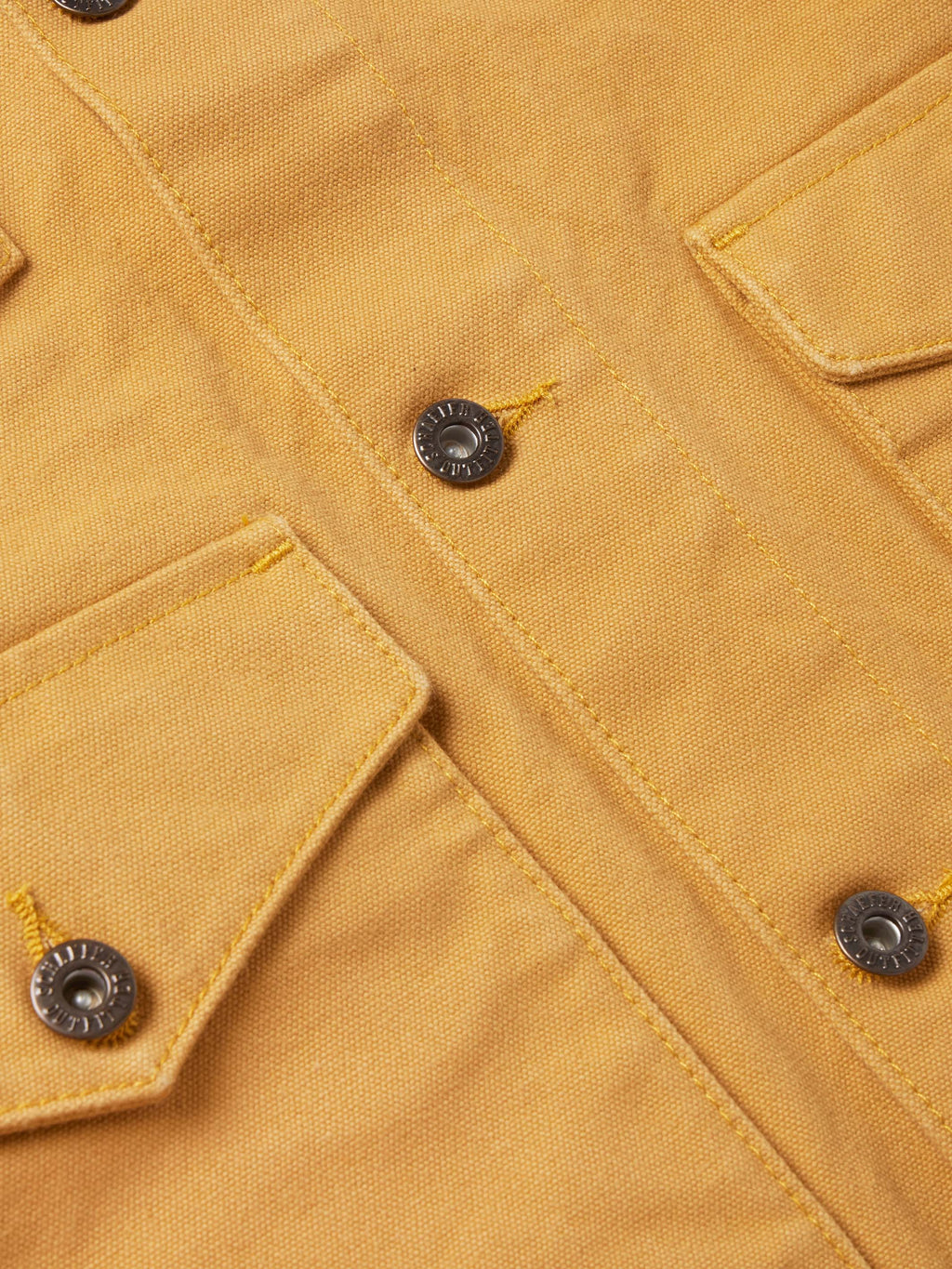 Suntan brush jacket close-up with button placket and metal snap details.