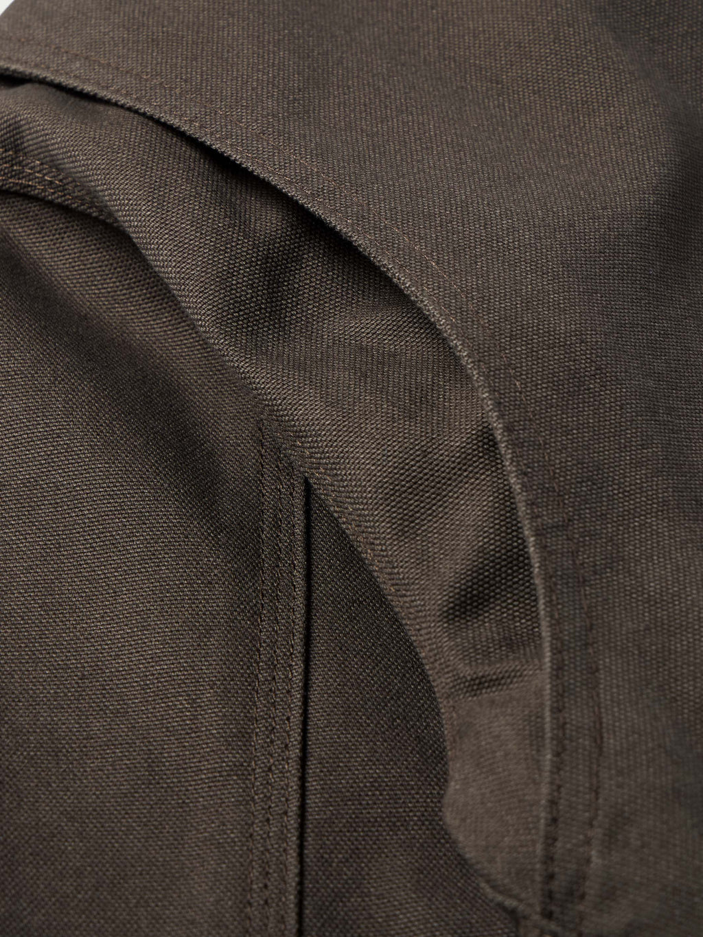 Dark brown canvas jacket shoulder seam and pocket edge close-up