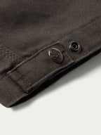 Brown canvas jacket cuff with metal button and stitched edge