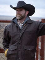 Dark brown canvas zip jacket worn by a cowboy with a hat and plaid shirt
