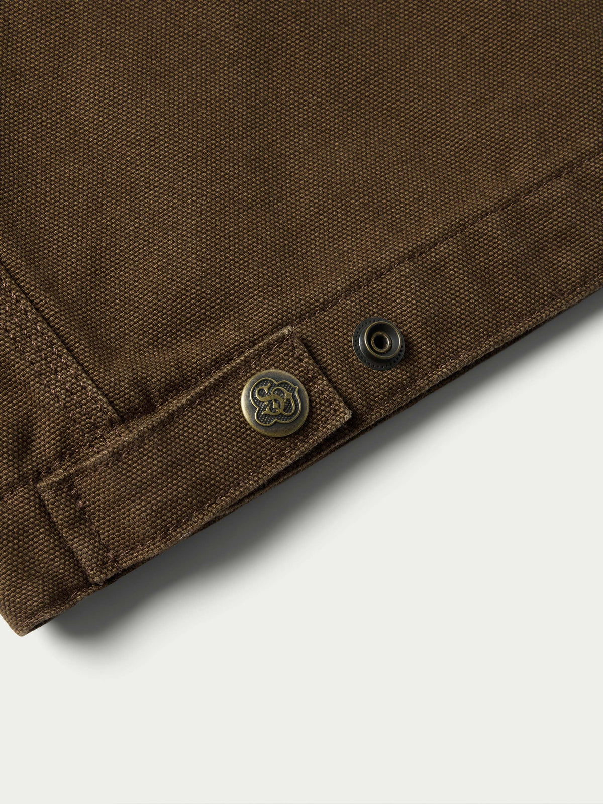 Hickory canvas jacket hem with snap buttons and small logo emblem