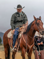 Dark green drifter jacket with brown leather-style collar worn outdoors by a rider