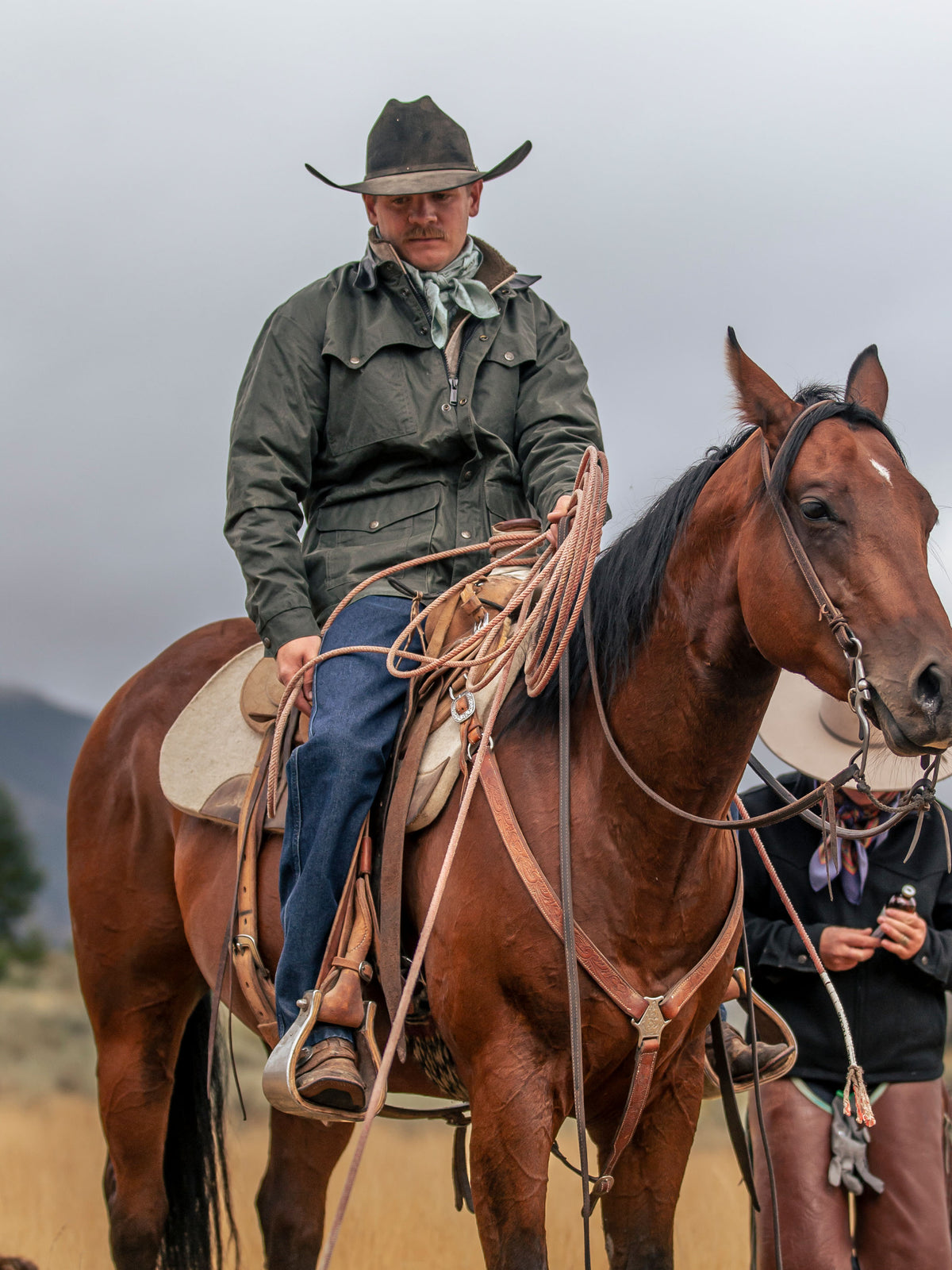 Dark green drifter jacket with brown leather-style collar worn outdoors by a rider