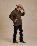 Oak-brown quilted zip jacket with stand collar and pockets, hands holding collar area.