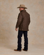 Oak-brown quilted jacket, zip front and pockets, seen from the side in full length.