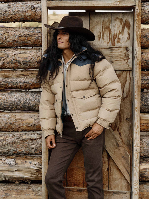 Man wearing camel and dark navy down jacket standing outdoors