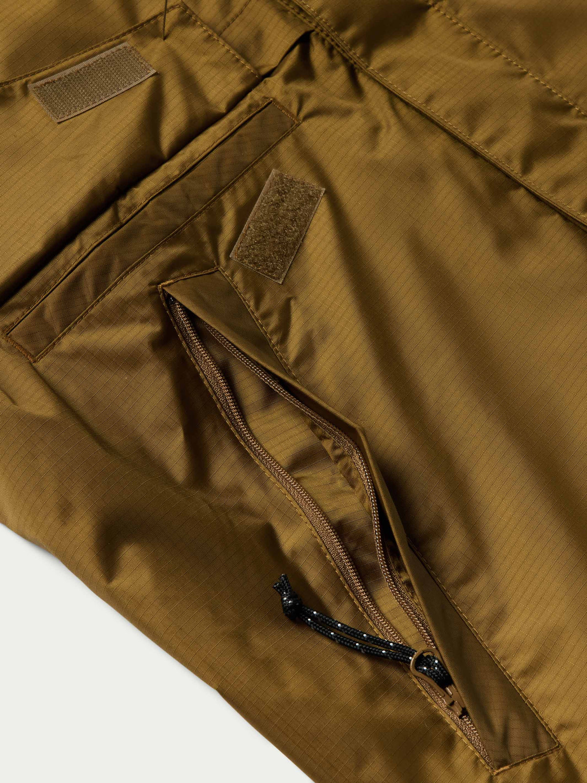 Brown rain jacket pocket and zipper detail with fabric tab