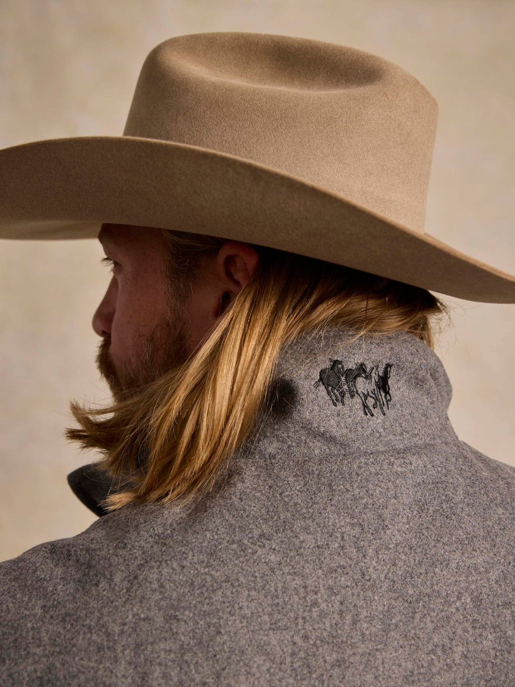 Heather gray wool vest with embroidered emblem at back neck, side view