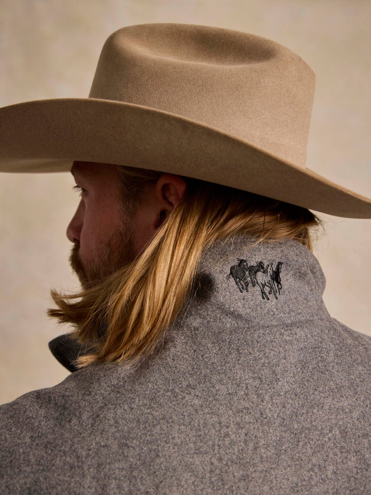 Heather gray wool vest with embroidered emblem at back neck, side view