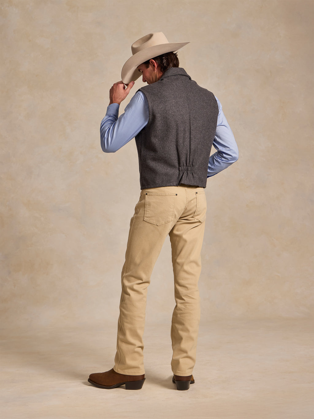 Man wearing charcoal wool vest; back view with gathered hem detail