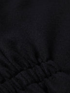 Black wool vest fabric close-up with stitched seam at the lower front