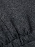 Charcoal wool vest close-up with gathered hem seam and textured fabric