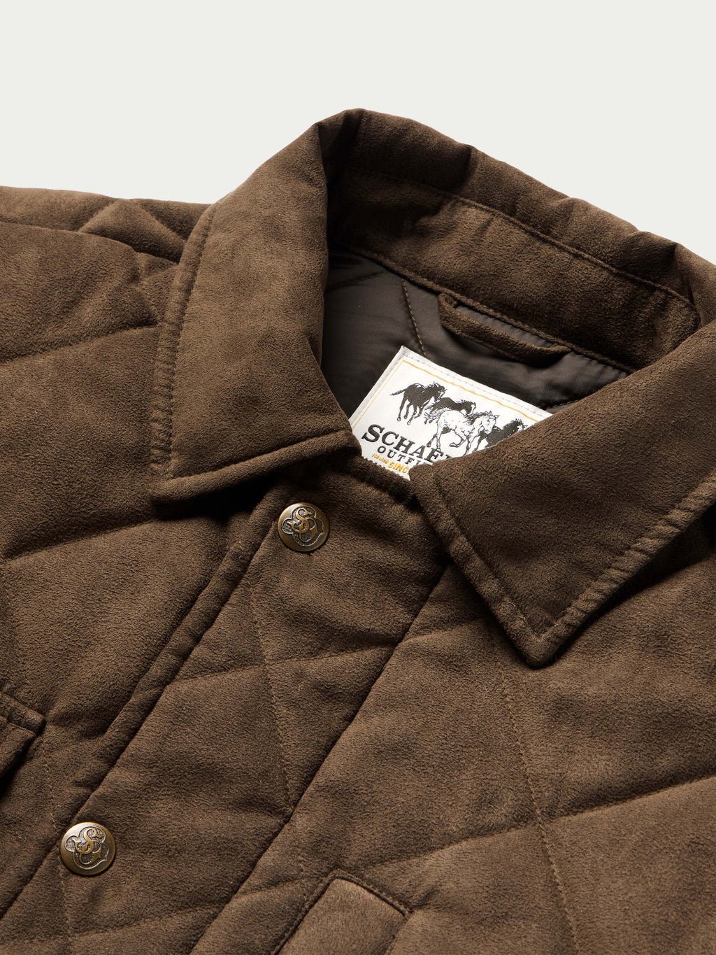 Brown quilted microsuede jacket detail with snap button placket and chest label patch.