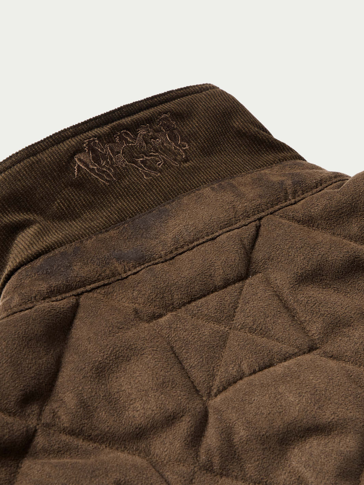 Brown quilted microsuede jacket interior collar lining with embroidered logo patch.
