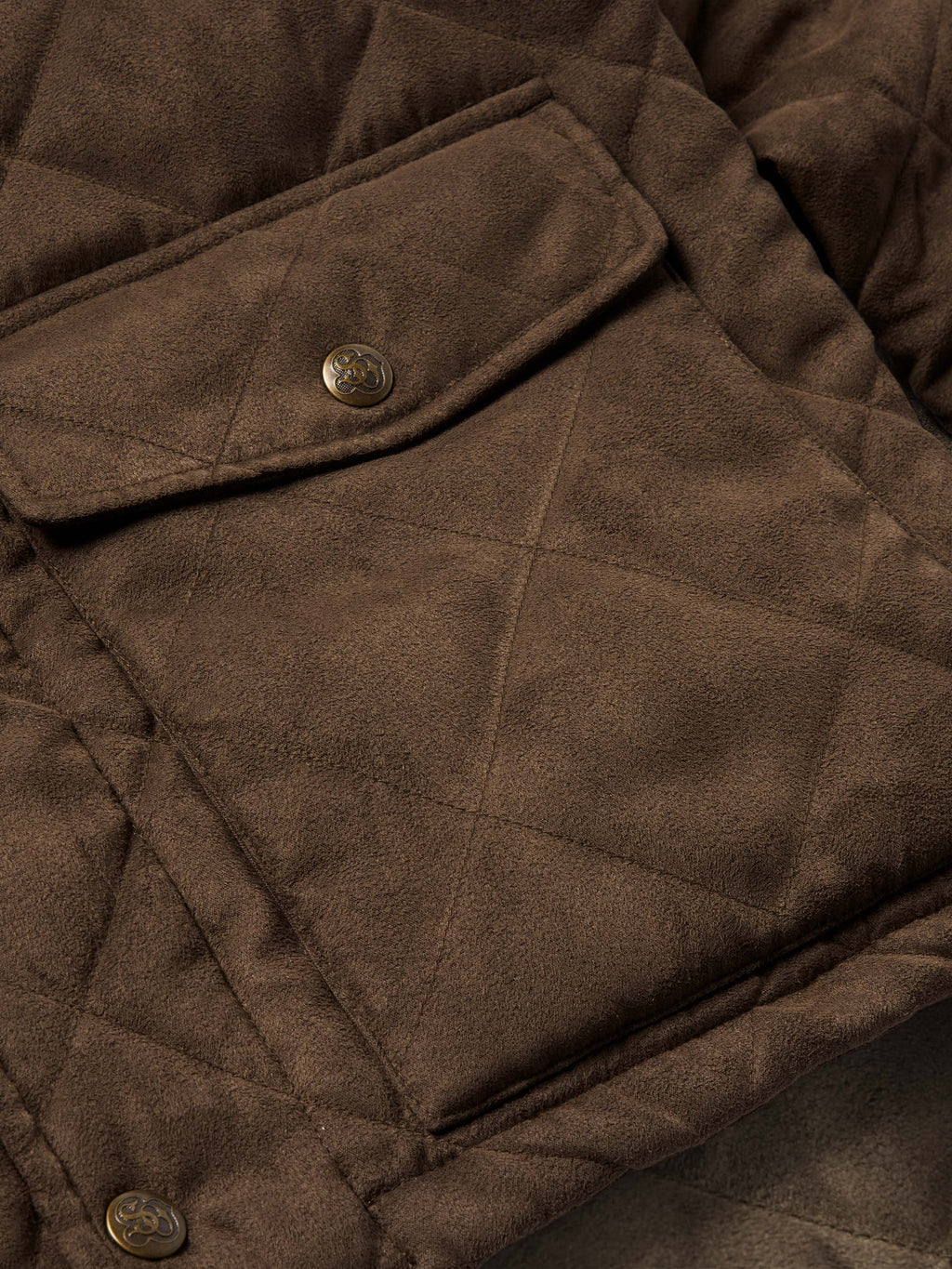 Close-up of brown quilted microsuede jacket chest pocket with metal snap buttons.