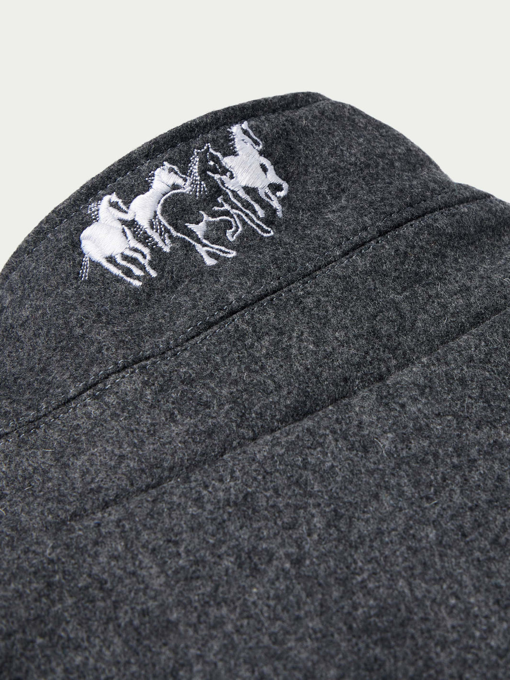 Charcoal wool coat shoulder with white embroidered horse logo