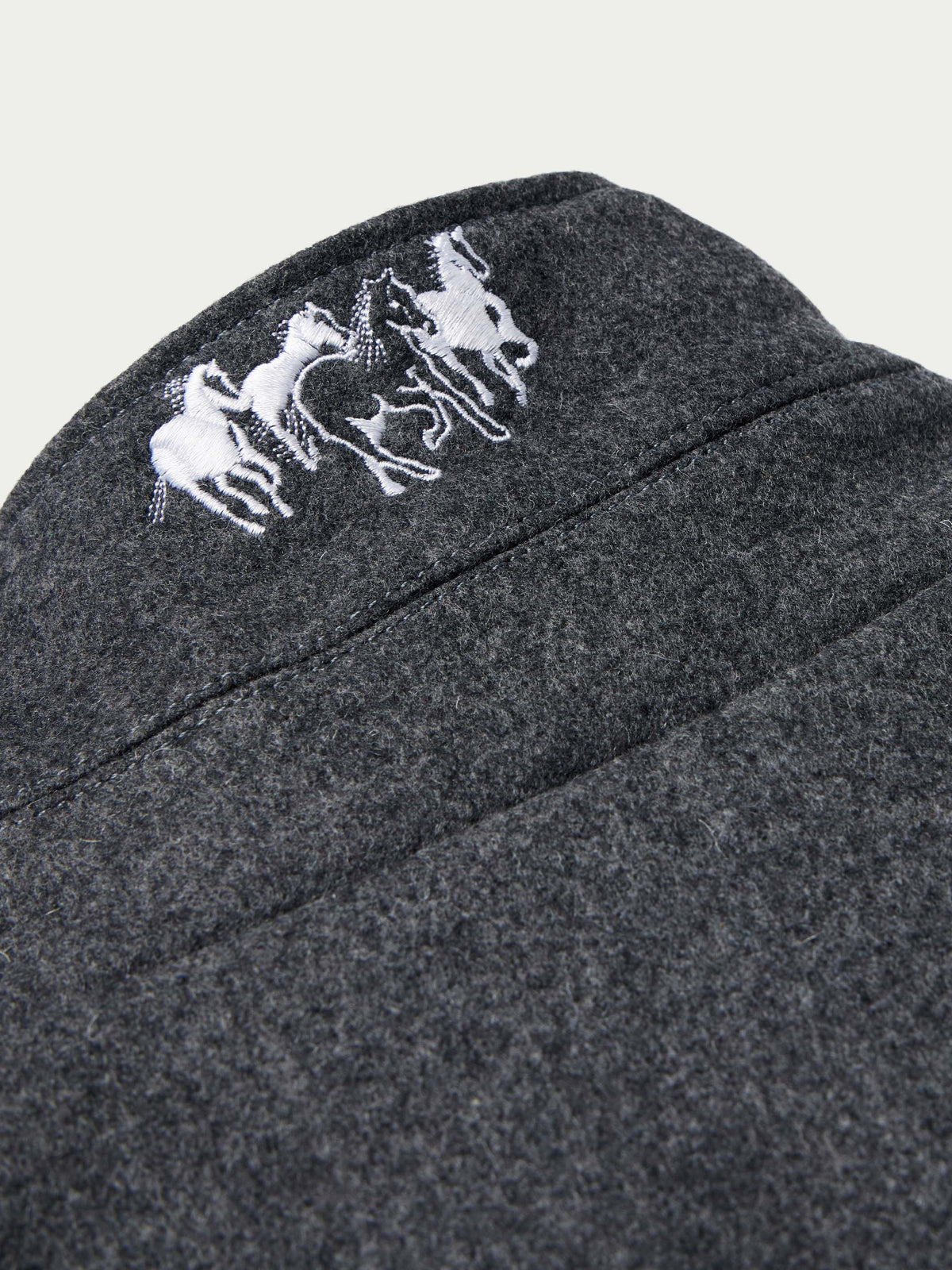 Charcoal wool coat shoulder with white embroidered horse logo