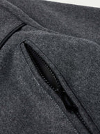 Charcoal wool coat detail: black zip pocket trim and stitched seam