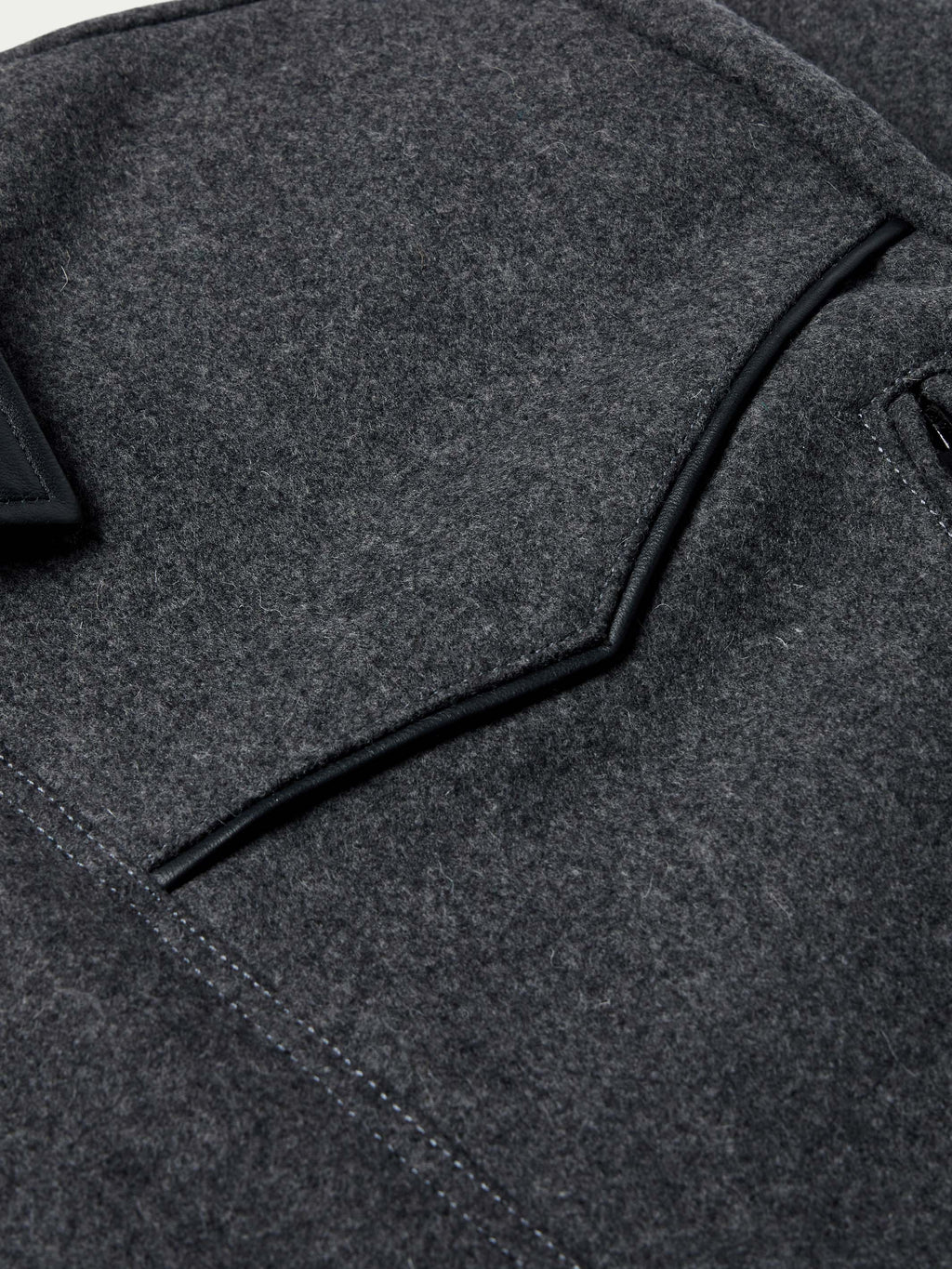 Charcoal wool coat detail: black piping along collar and shoulder panel