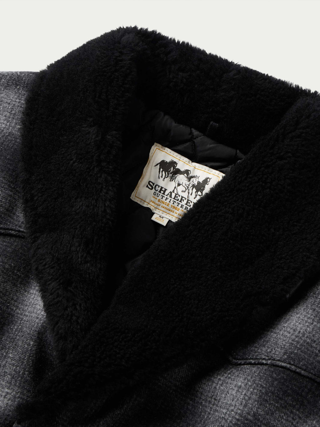 Black wool coat with shearling-style collar, interior label visible