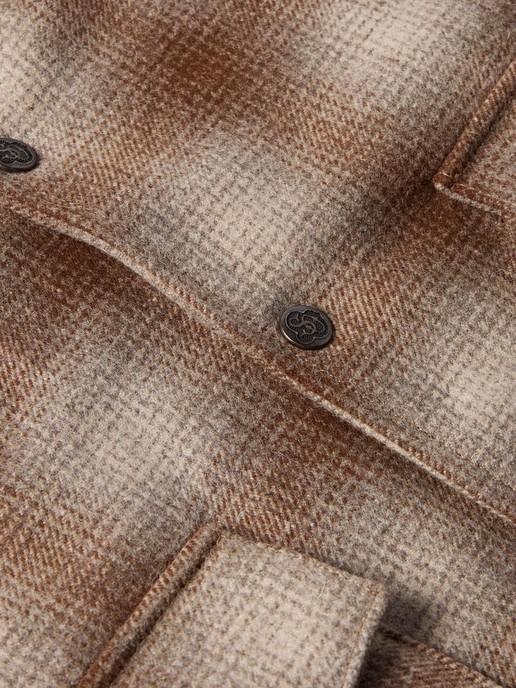 Taupe wool coat close-up: plaid weave with dark button and welt pocket details