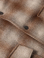 Taupe wool coat close-up: plaid weave with dark button and welt pocket details