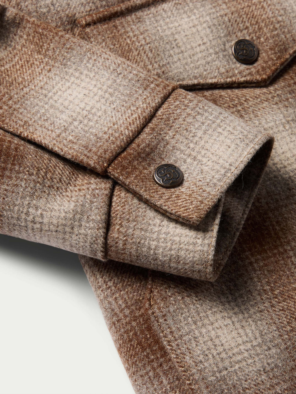 Taupe wool coat sleeve and cuff close-up with dark buttons and stitched seams