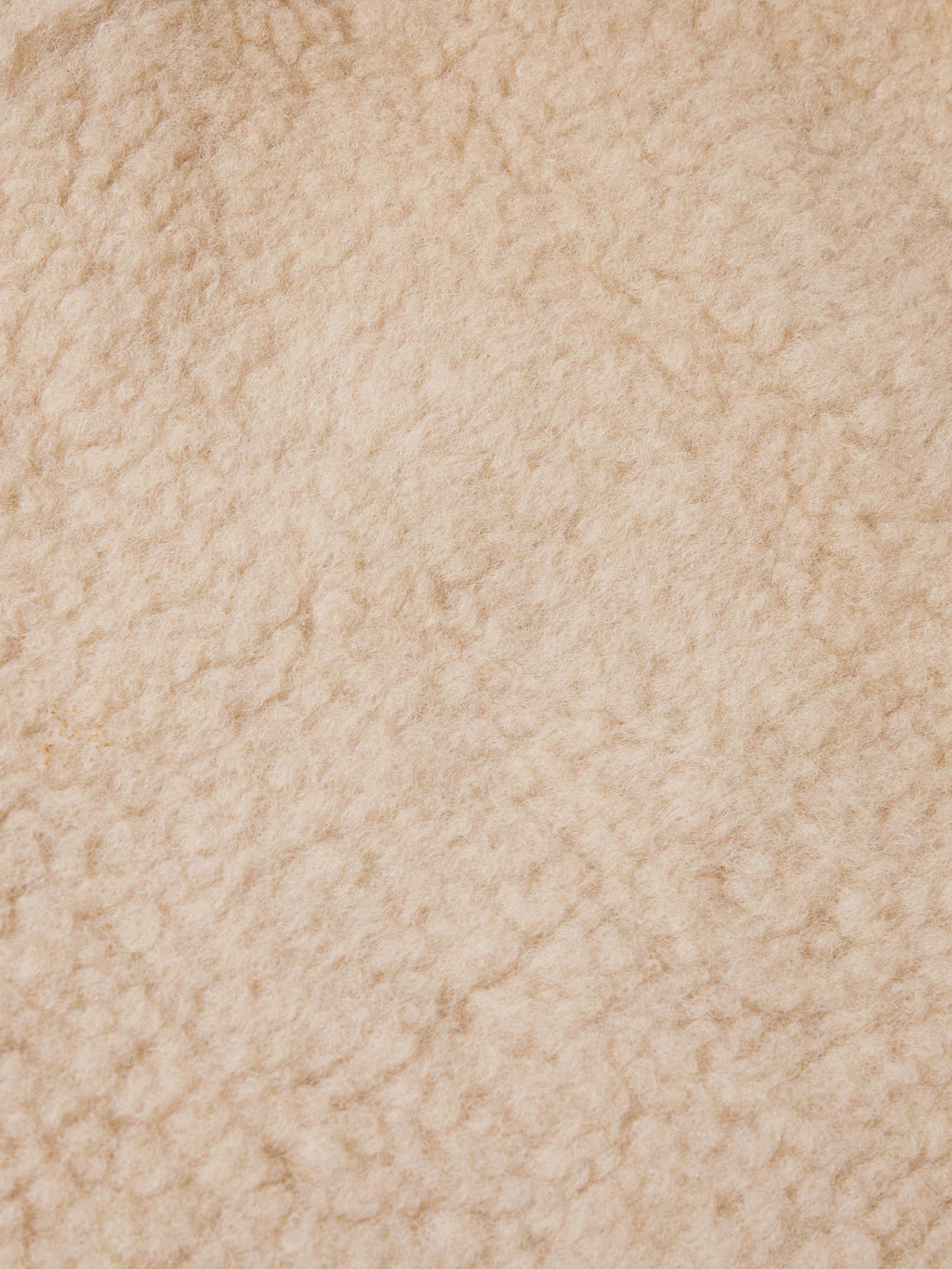 Close-up of cream shearling fabric texture, soft and plush surface