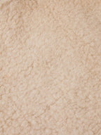 Close-up of cream shearling fabric texture, soft and plush surface