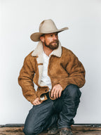 Buckskin shearling coat with white shearling collar, button front, and side pockets