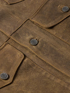 Tan leather jacket close-up with snap placket and textured stitch seams.
