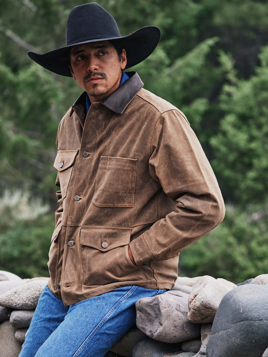 Tan leather brush jacket worn by a man with dark collar and shoulder flap pockets.