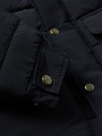 Close-up of navy jacket front with buttoned flap pockets and snap placket