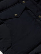 Close-up of navy puffer jacket placket with snap buttons and stitched seam
