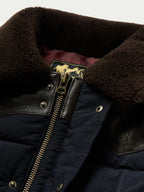 Navy puffer jacket collar detail with brown leather trim and gold-tone zipper