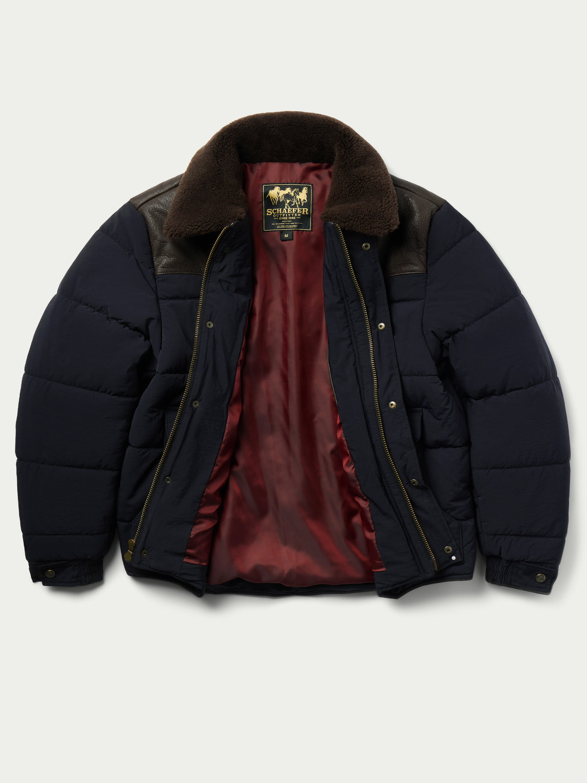 Navy puffer jacket with brown sherpa collar, interior lining visible with zip pull