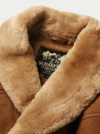 Brown shearling coat interior: fleece lining and brand tag at neckline opening.