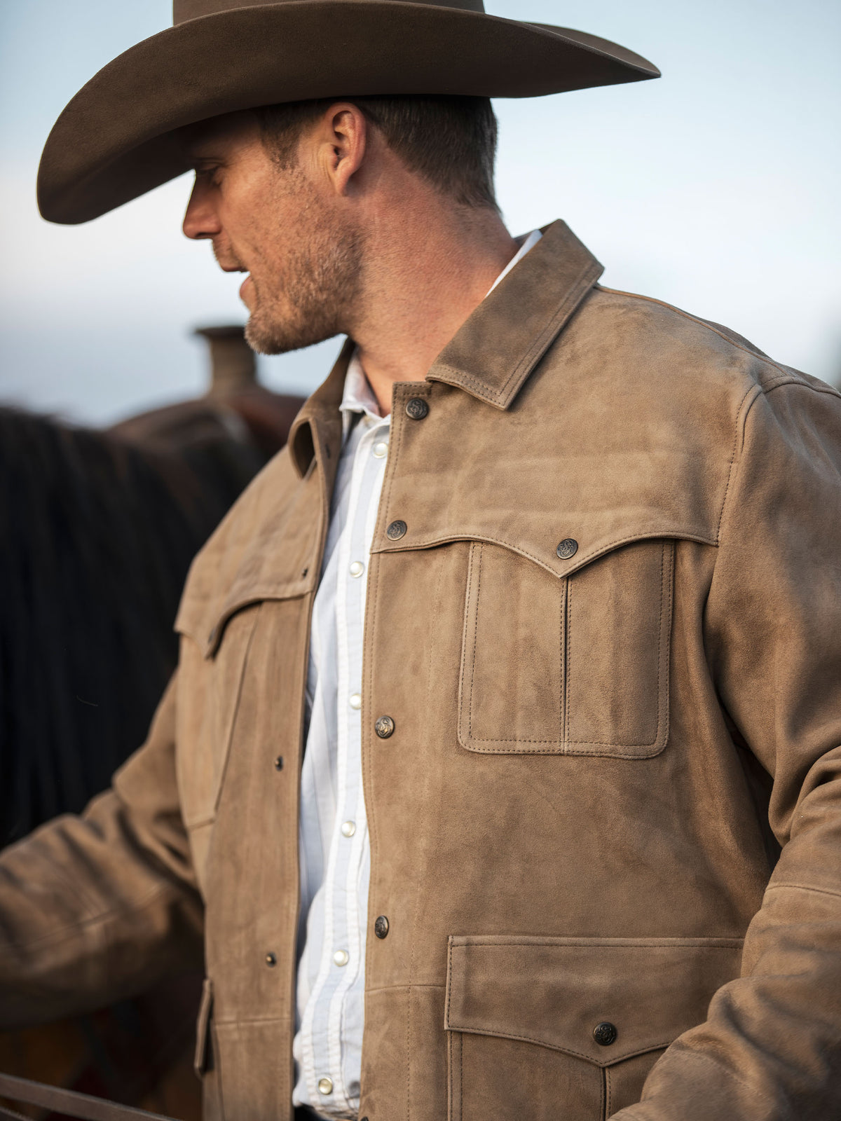 Desert tan suede shirt jacket worn by a man, showing chest pockets and snaps