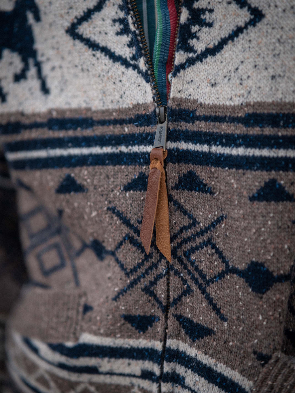 Close-up of zipper and tan pull on navy-and-cream Fair Isle knit sweater.