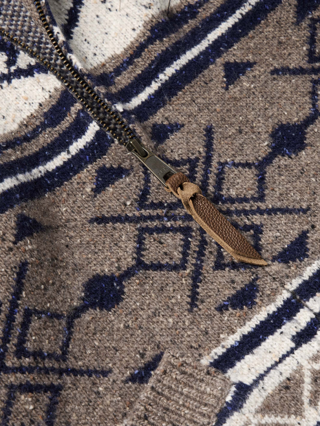 Close-up of navy and white motifs on brown knit full-zip sweater.