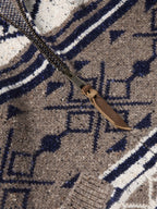 Close-up of navy and white motifs on brown knit full-zip sweater.