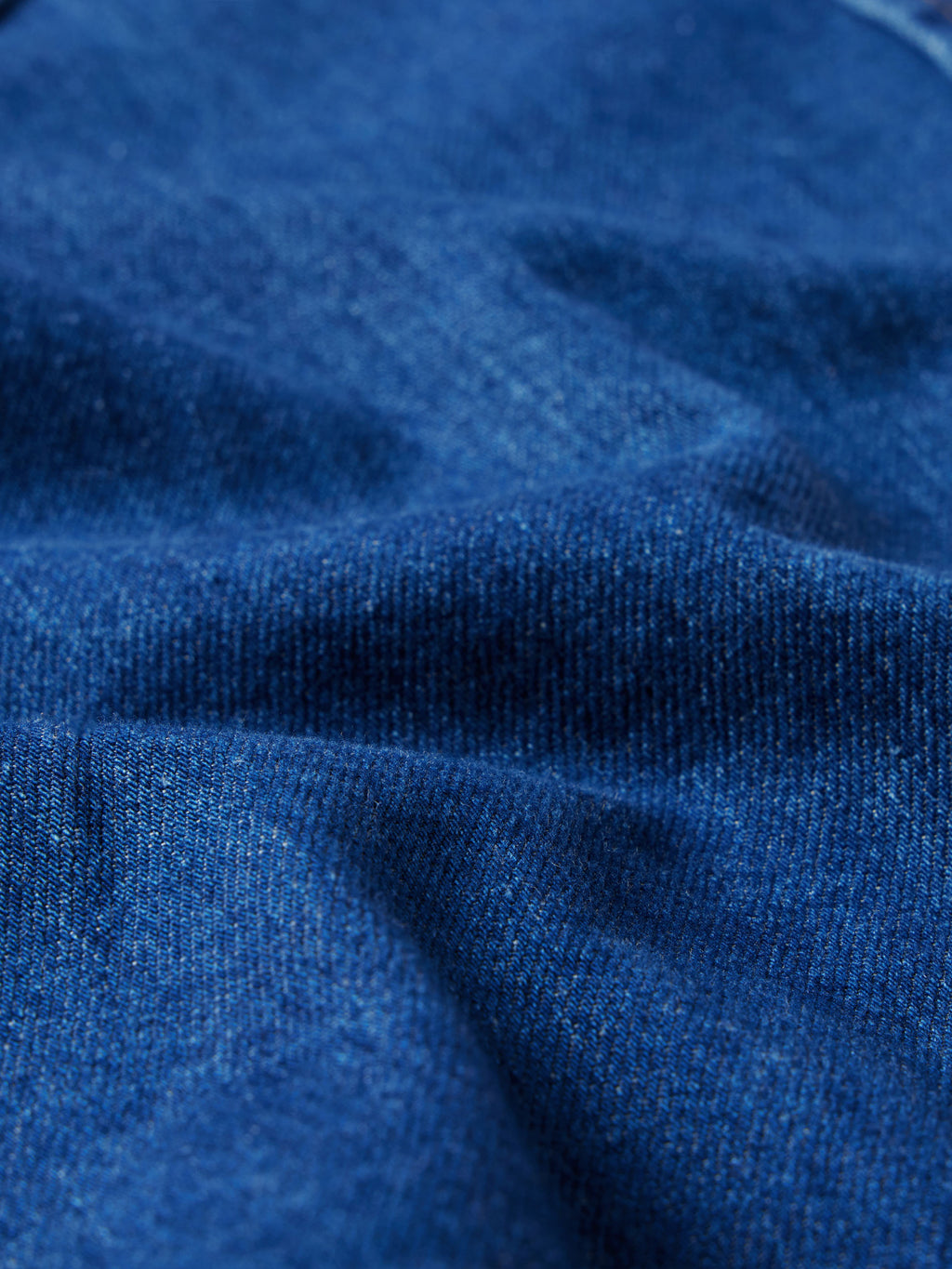 Indigo denim fabric close-up with visible weave and subtle topstitching