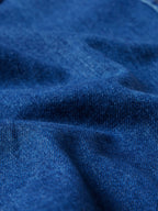 Indigo denim fabric close-up with visible weave and subtle topstitching