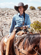 Woman wearing light wash denim pearl snap western shirt with front button placket