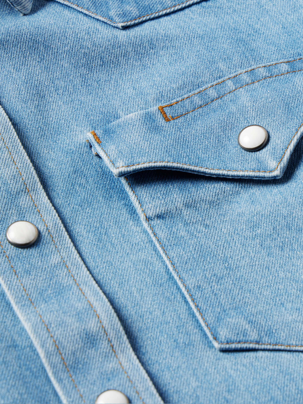 Light wash denim western shirt close-up of pearl snap placket and stitched details
