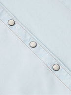 Light wash denim snap shirt sleeve placket with three metal snaps and orange stitching